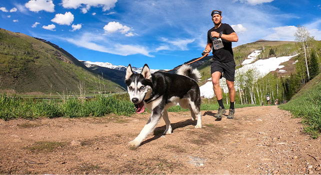 Guy trail running with dog. Photo Credit: Andrew Taylor