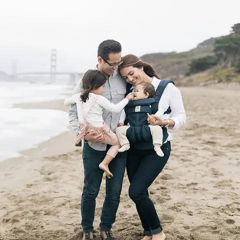 Family on the beach using the Omni Breeze Baby Carrier