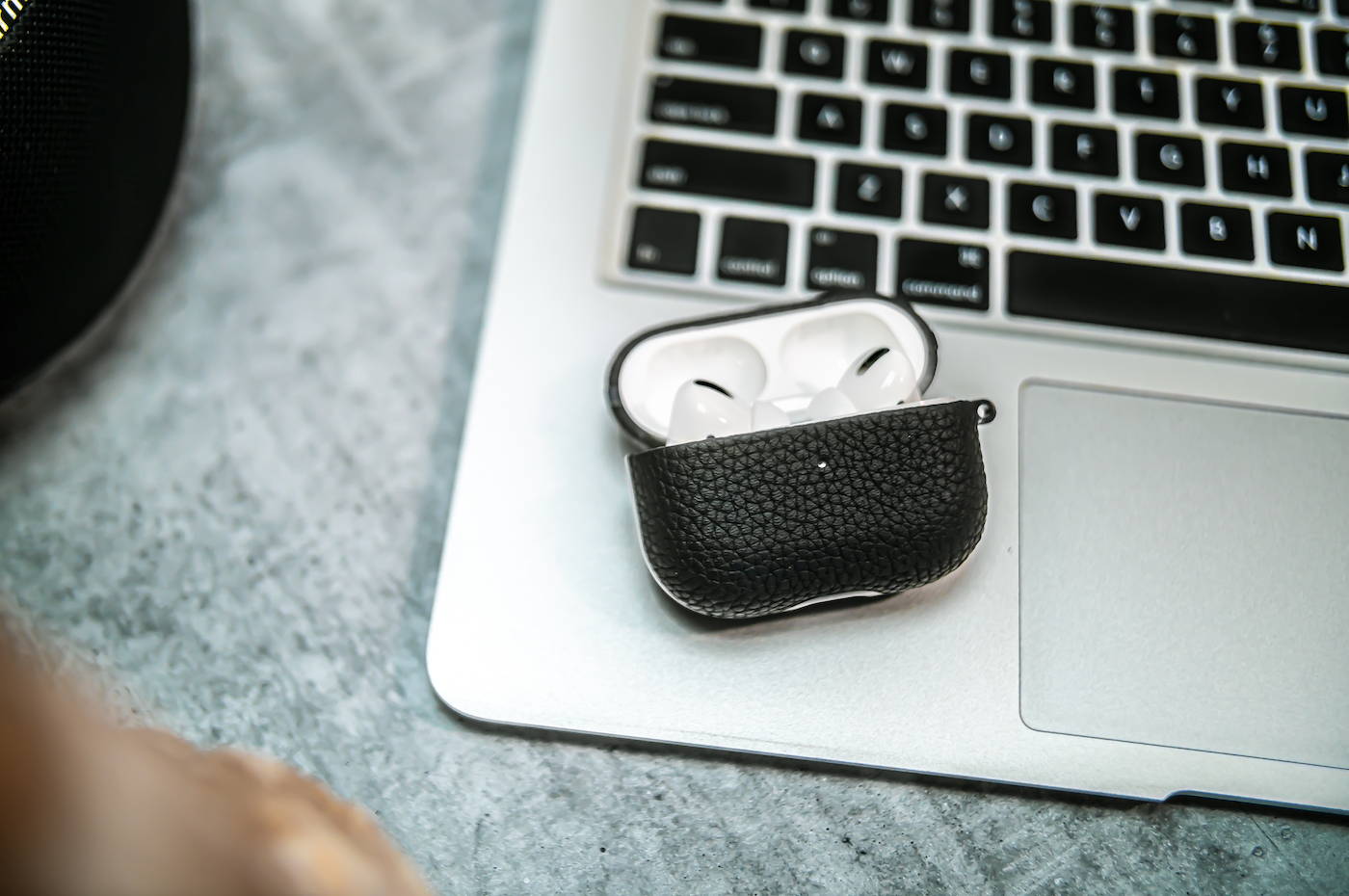 black genuine leather airpods pro case laying on a macbook air with lid open