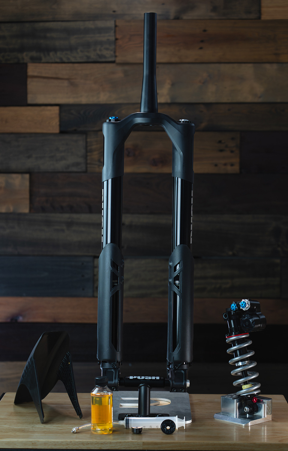 Mountain bike fork with various mechanical components on a wooden surface.
