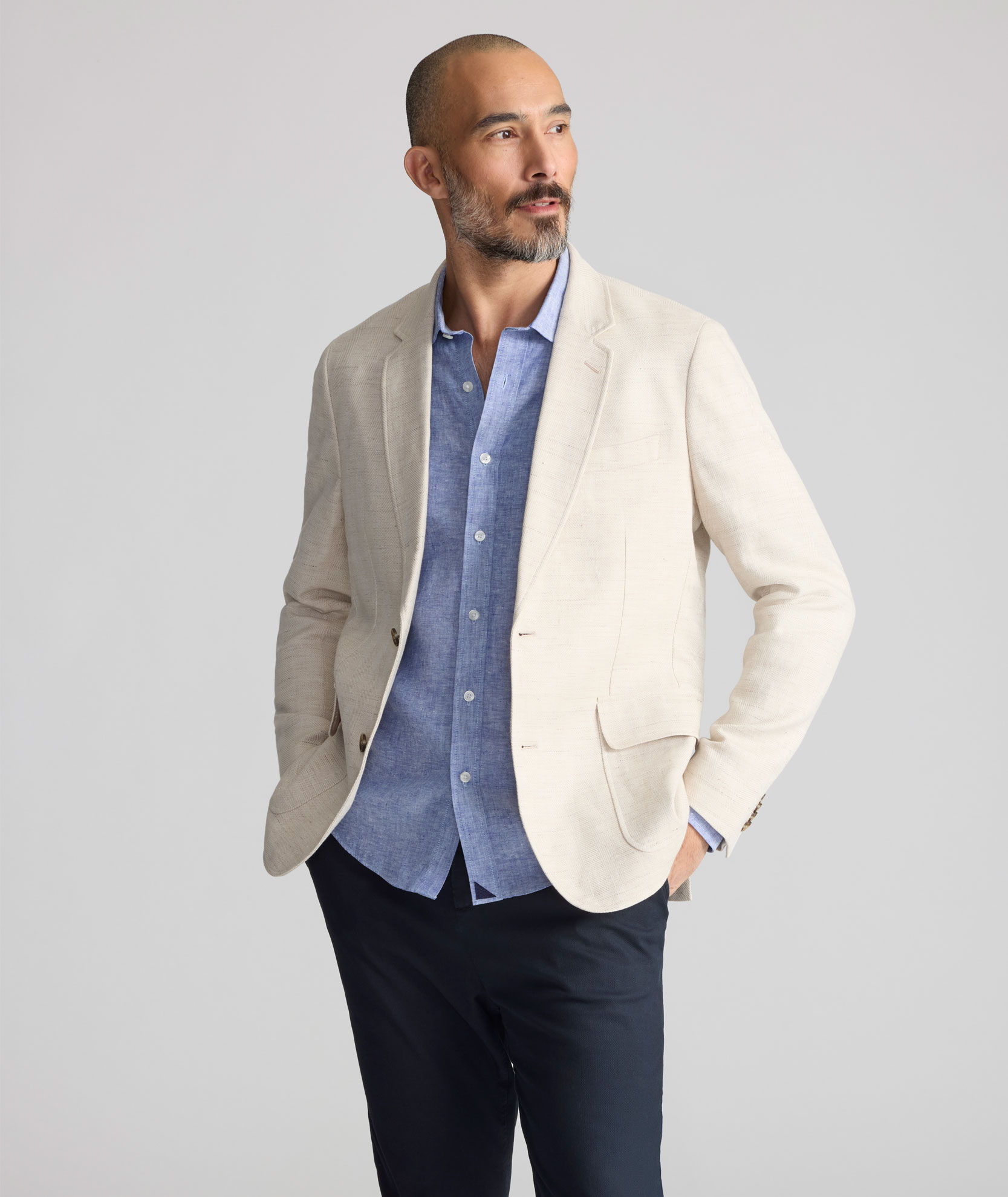 Man wearing a light blazer over a blue shirt, posing confidently.