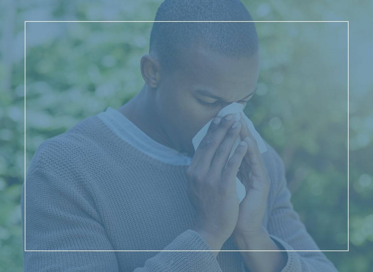 Man blowing his nose – does he have a cold or could it be the symptoms of seasonal allergies?