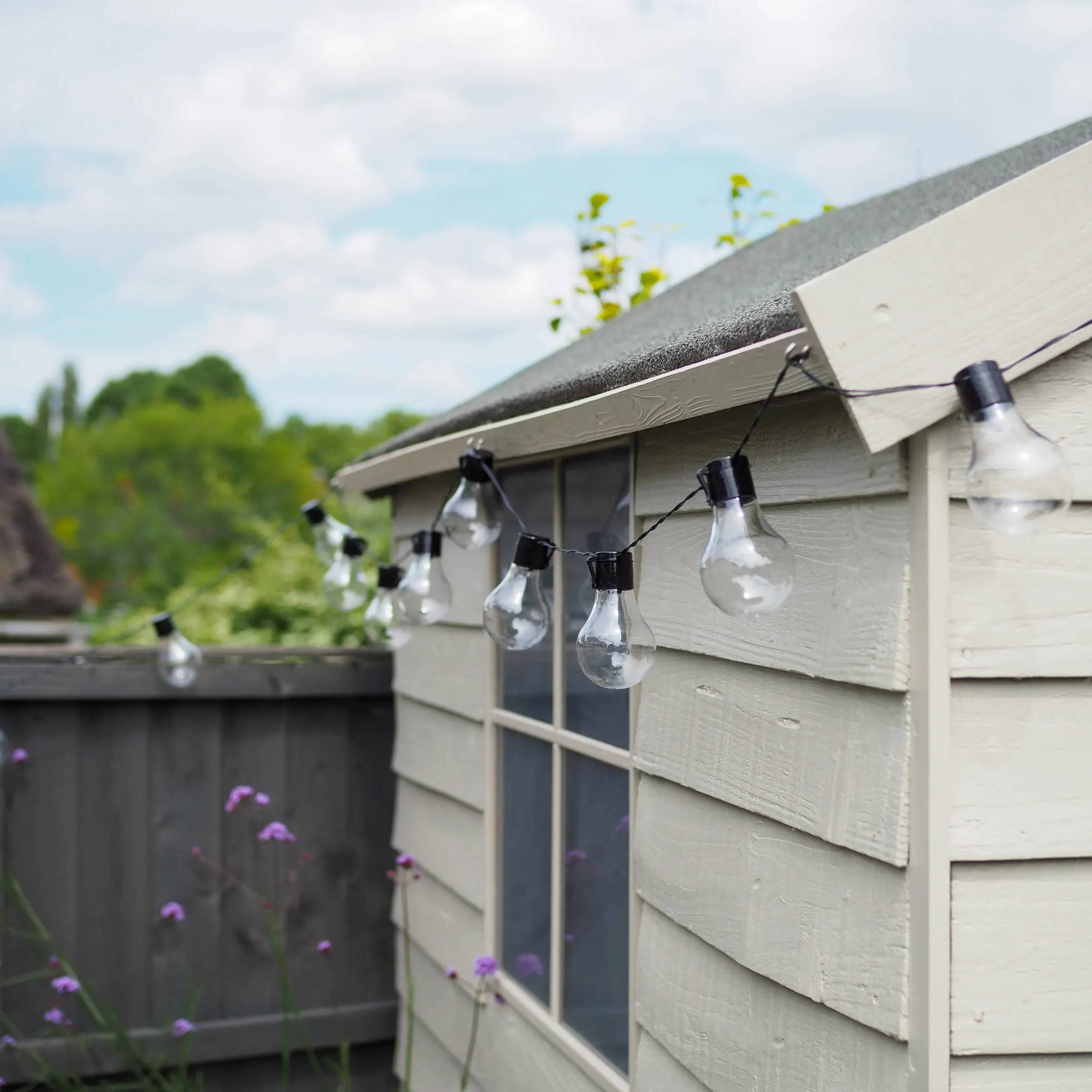Close up of solar festoon lights on a garden shed during the day.