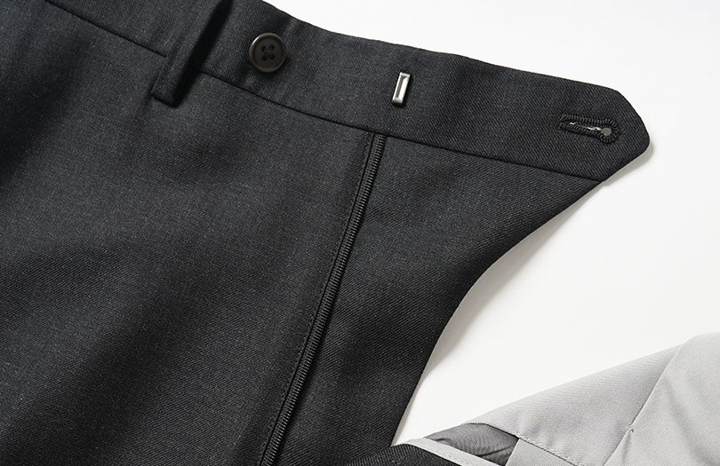 Black pants with a button and zipper detail, laid flat.