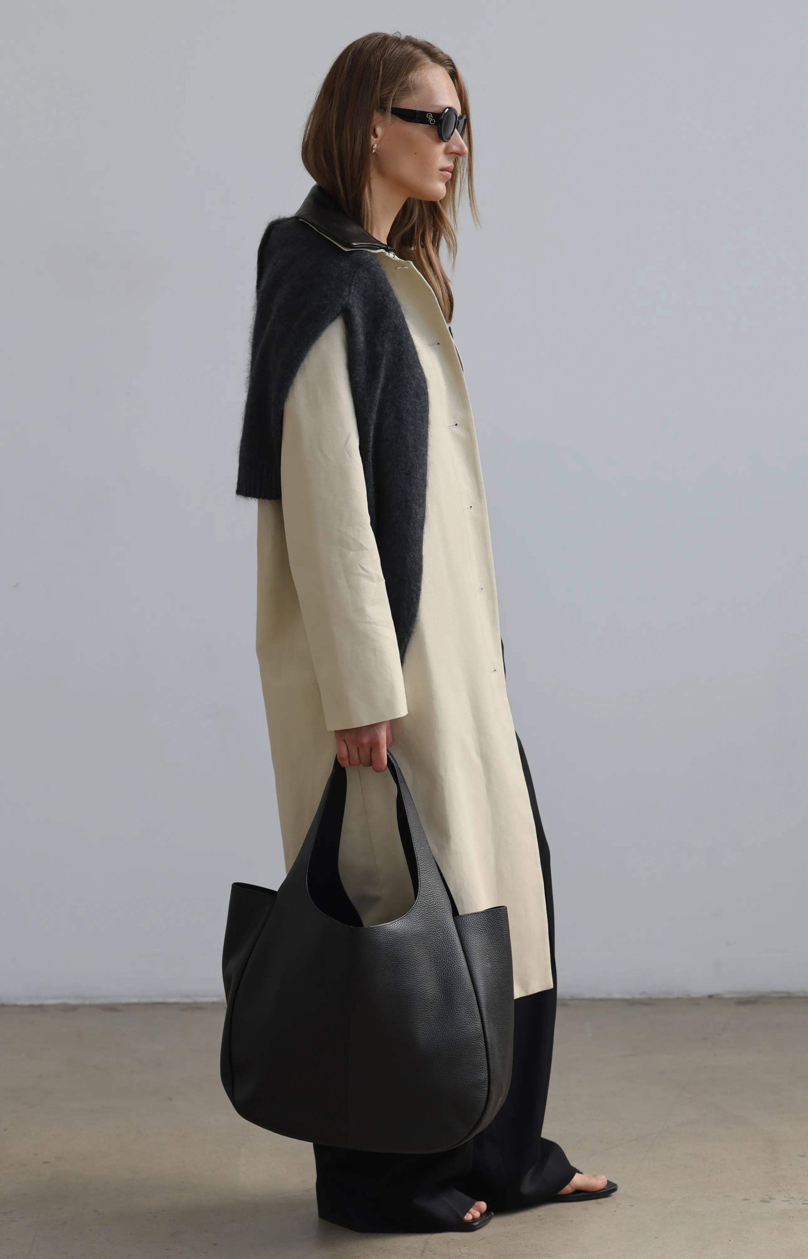 A woman in a long coat with a large black bag.