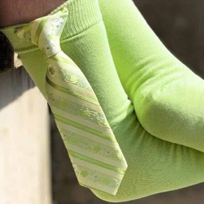 A man wearing lime green socks with a tie clipped on the side