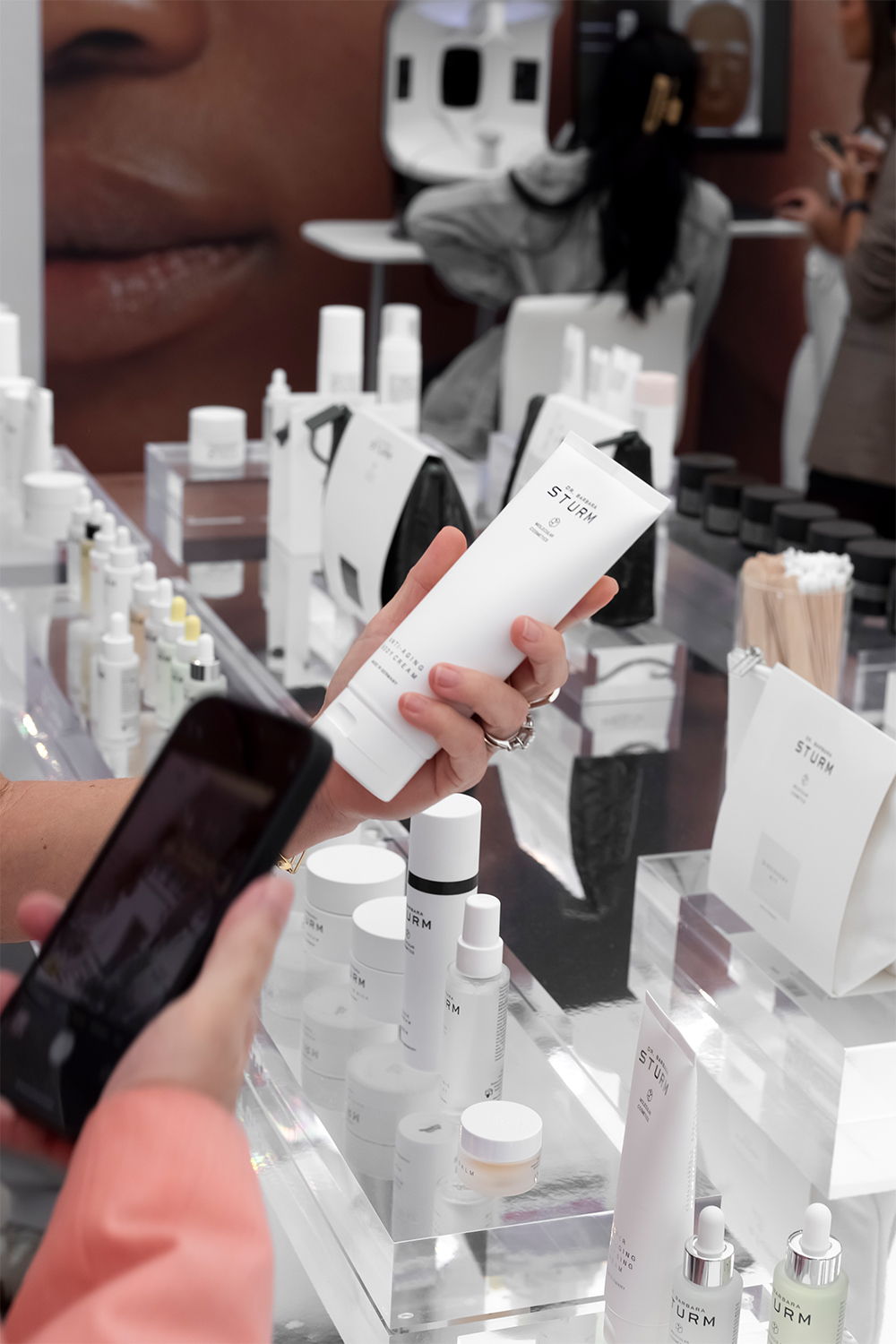 Person holding a skincare product while taking a photo in a store.