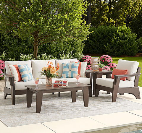 Outdoor seating area with cushions, table, and decorative plants.