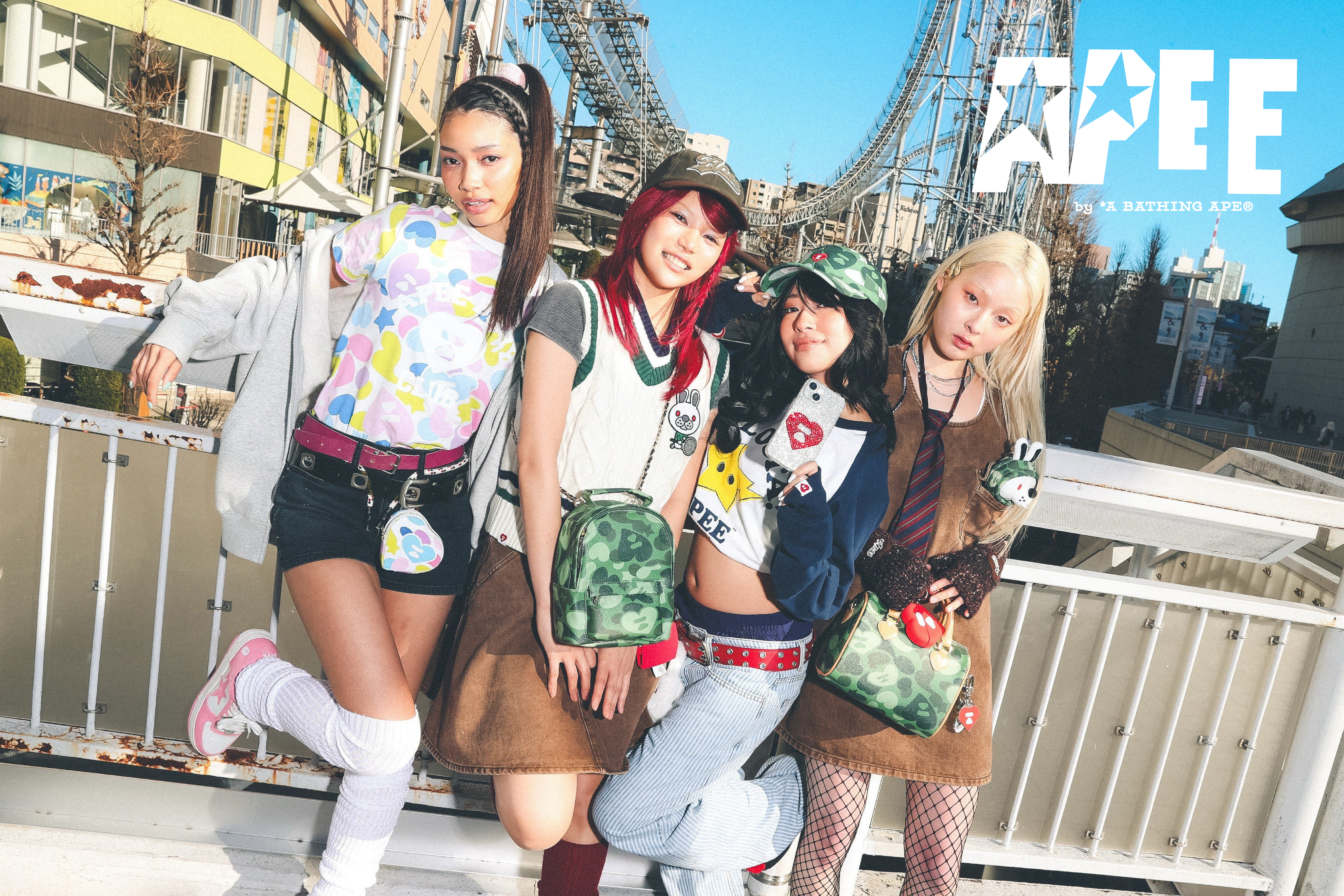 Four friends posing together in trendy outfits at an amusement park.