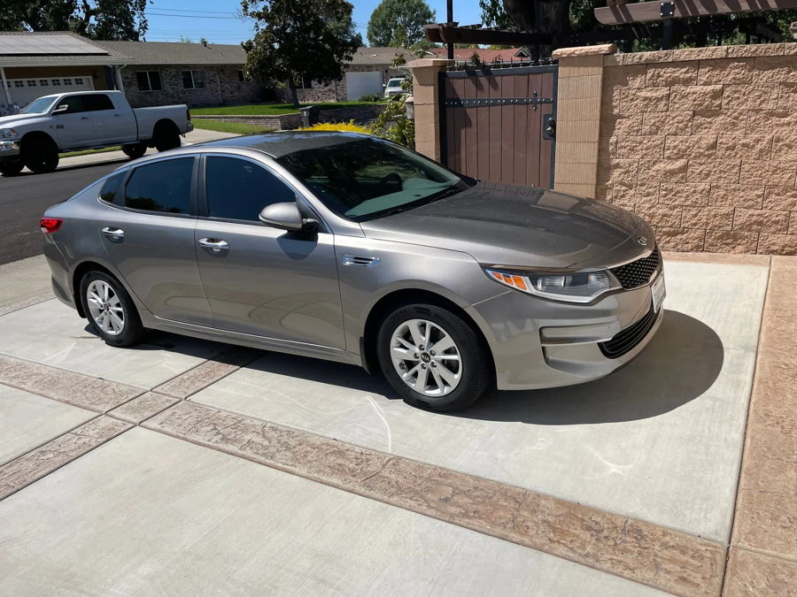 Side profile Jeff's silver 2016 Kia Optima sedan parked on stamped concrete driveway photo 1