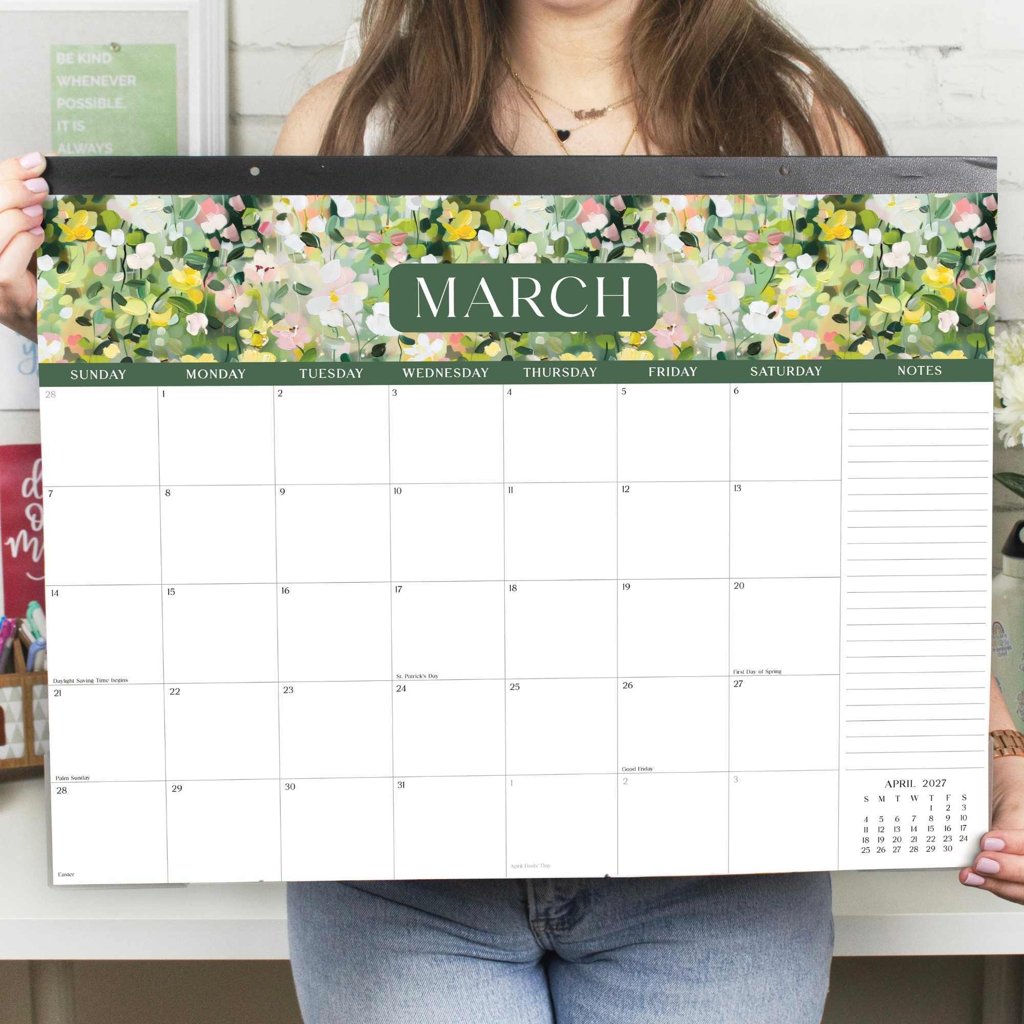 A large, floral patterned 2027 calendar being held by a woman in jeans