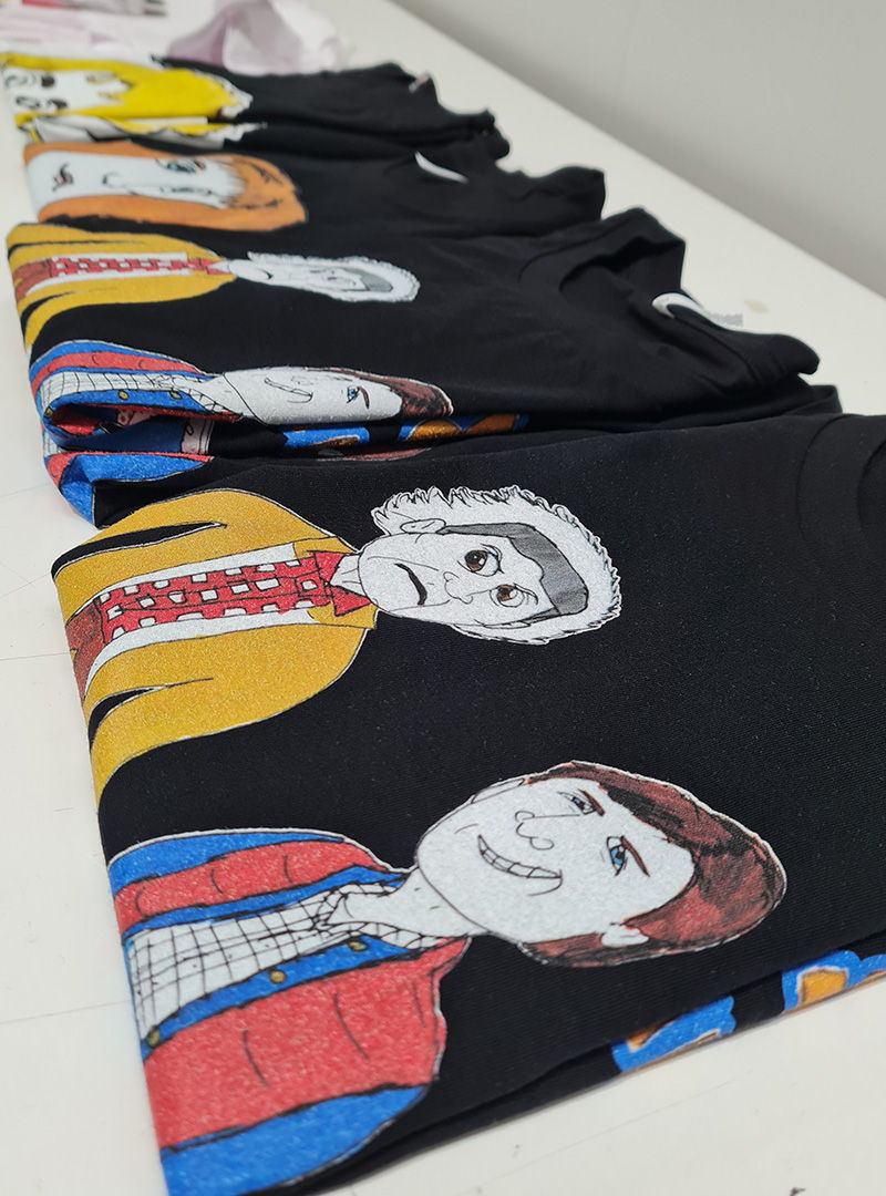 Folded t-shirts featuring portrait-style illustrations of people with fine pen ines and colour blocking.