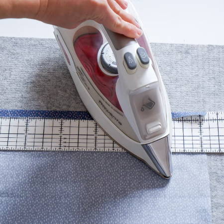 ironing a hem with a hot hem ruler on a wool pressing mat