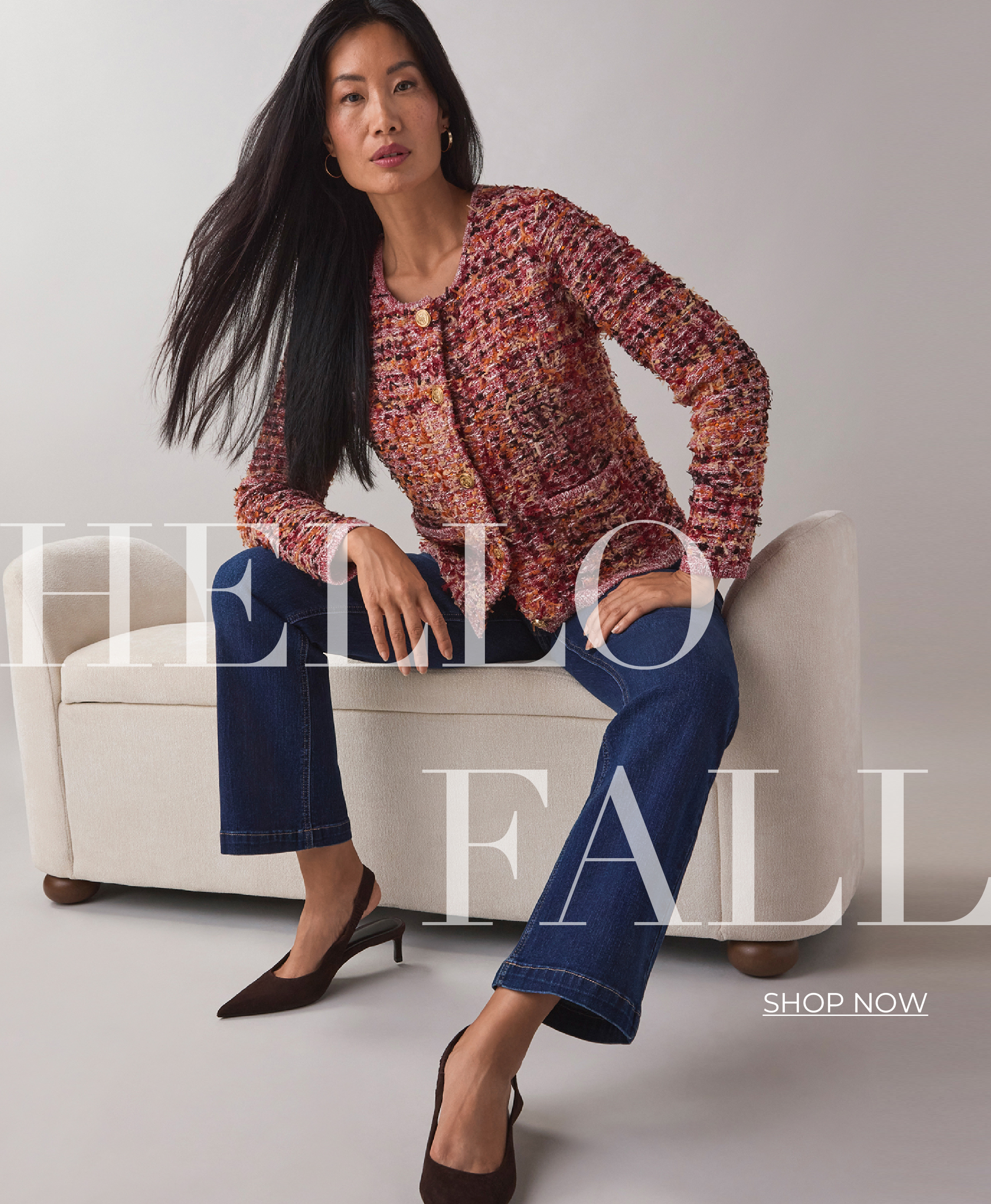 Model wearing a patterned top and jeans, seated on a couch with 
