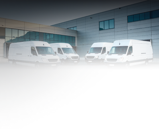 Four white delivery vans parked in front of a building.