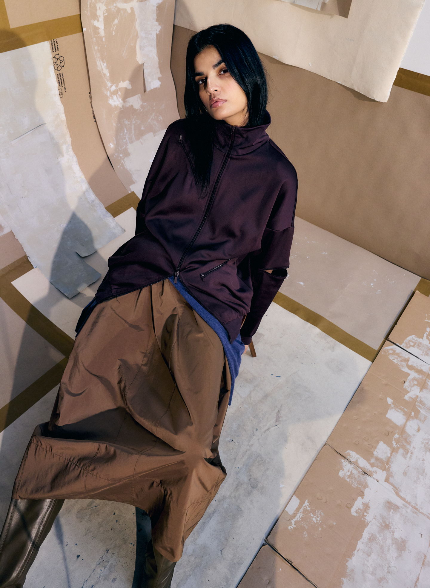Person in stylish outfit seated on a geometric background.