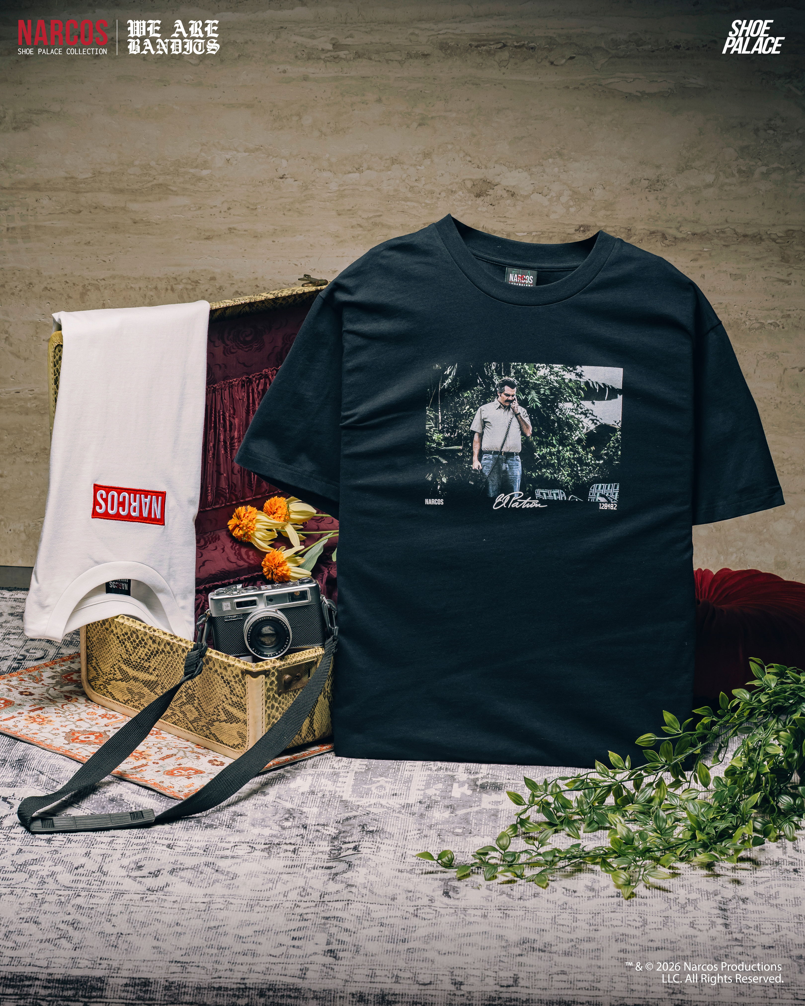 Black t-shirt with graphic, camera, flowers, and accessories on a textured surface.