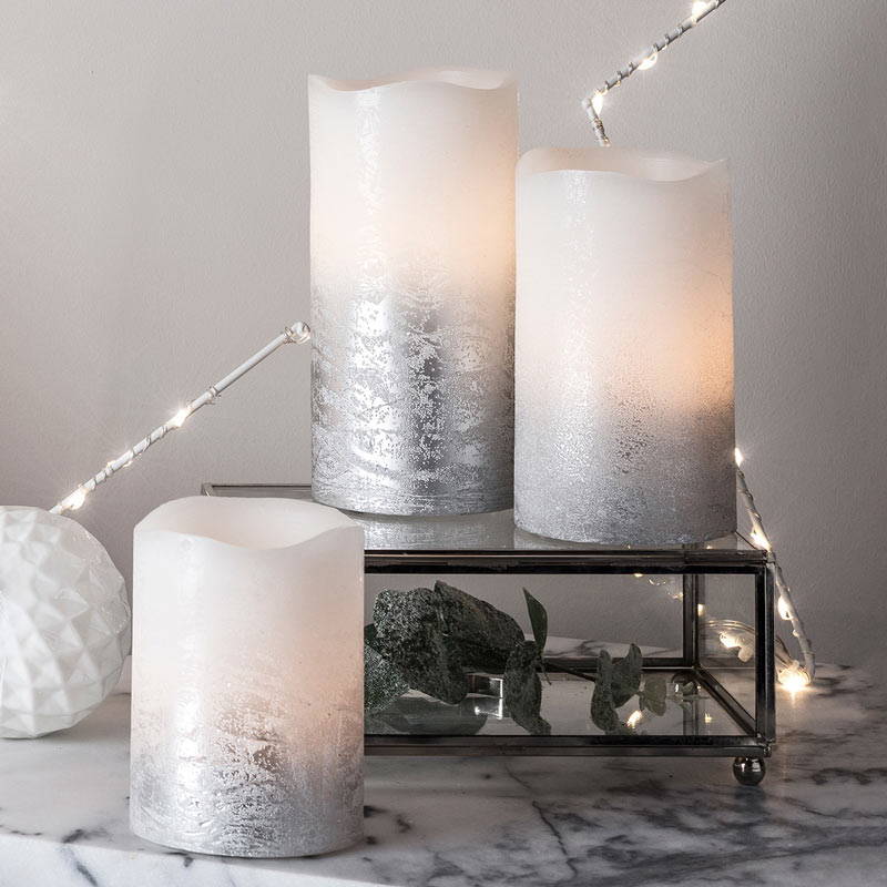 Silver LED Christmas candles on a marble countertop.