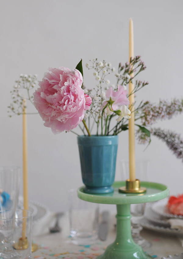Fresh flowers styled in a Mosser tumbler on a cakestand for the wedding table.