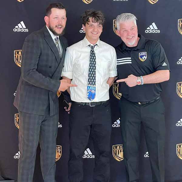 A teen wearing a custom soccer tie with his coaches
