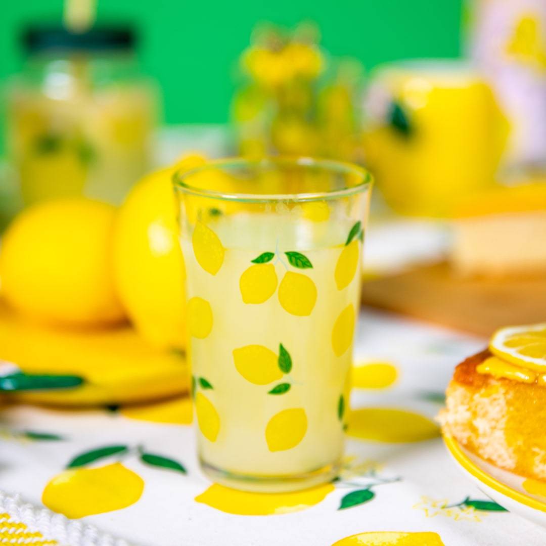 A refreshing setting with a lemon-themed glass filled with lemonade, showcasing lemon prints on the tablecloth and a cheerful yellow and green color scheme.