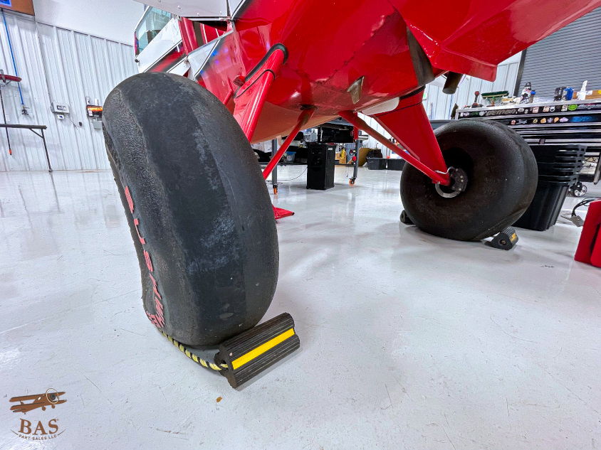 Red aircraft tire resting on a yellow wheel chock in a hangar.