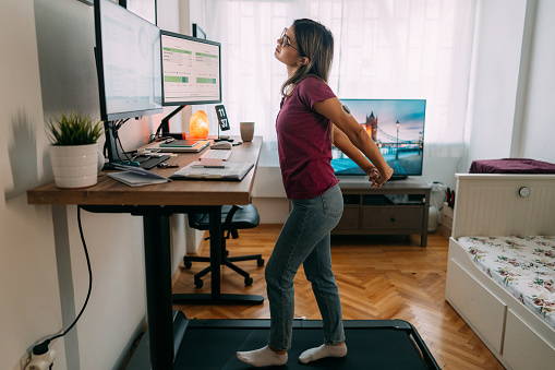 Woman standing. Treadmill desk. Compression socks. Therafirm.