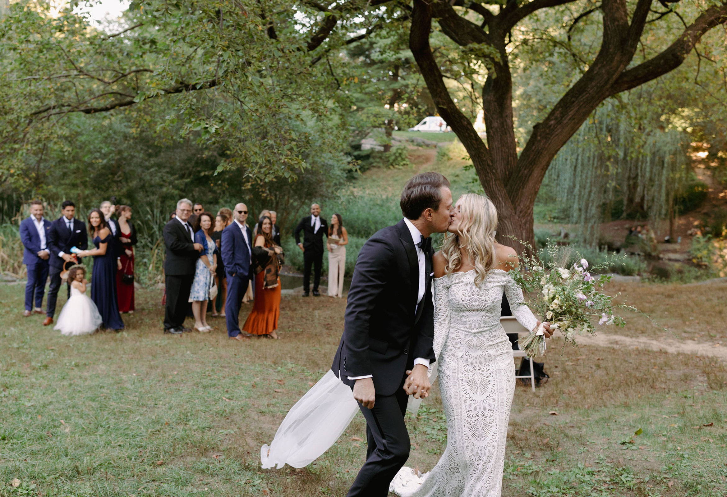 Novios besándose con la fiesta nupcial de fondo