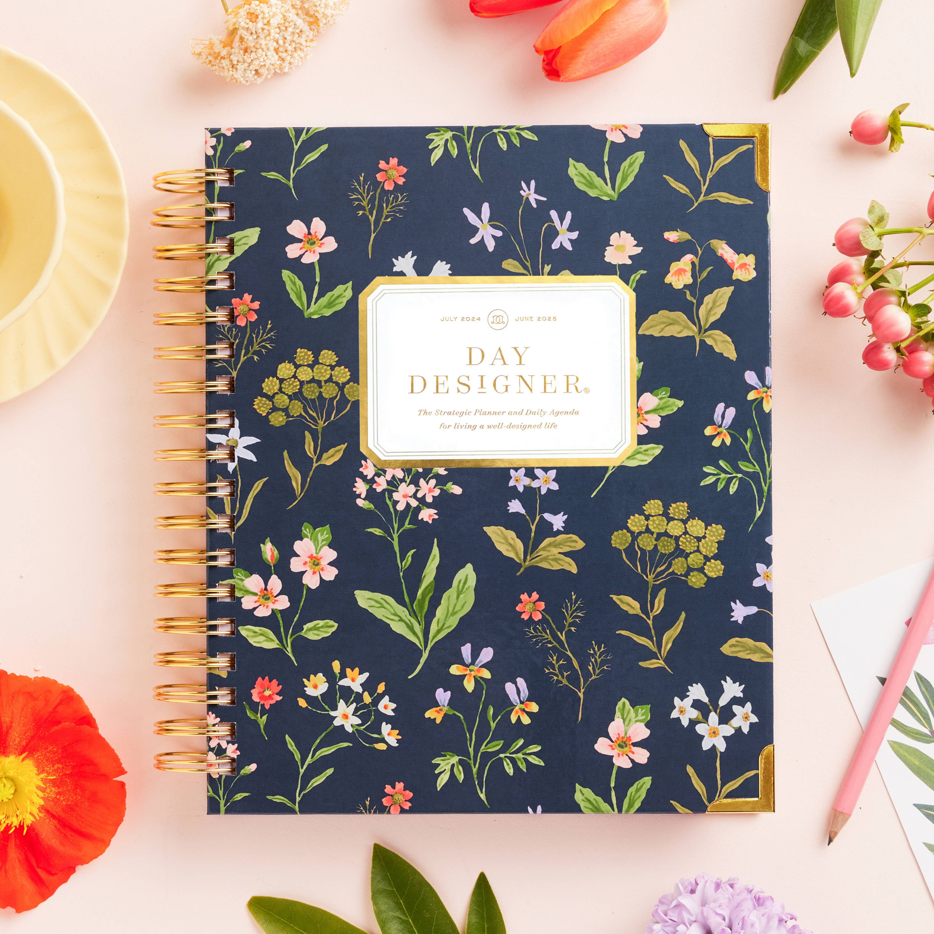 navy blue floral closed book planner with pretty flowers on beige background, with assorted flowers, dish and pink pencil