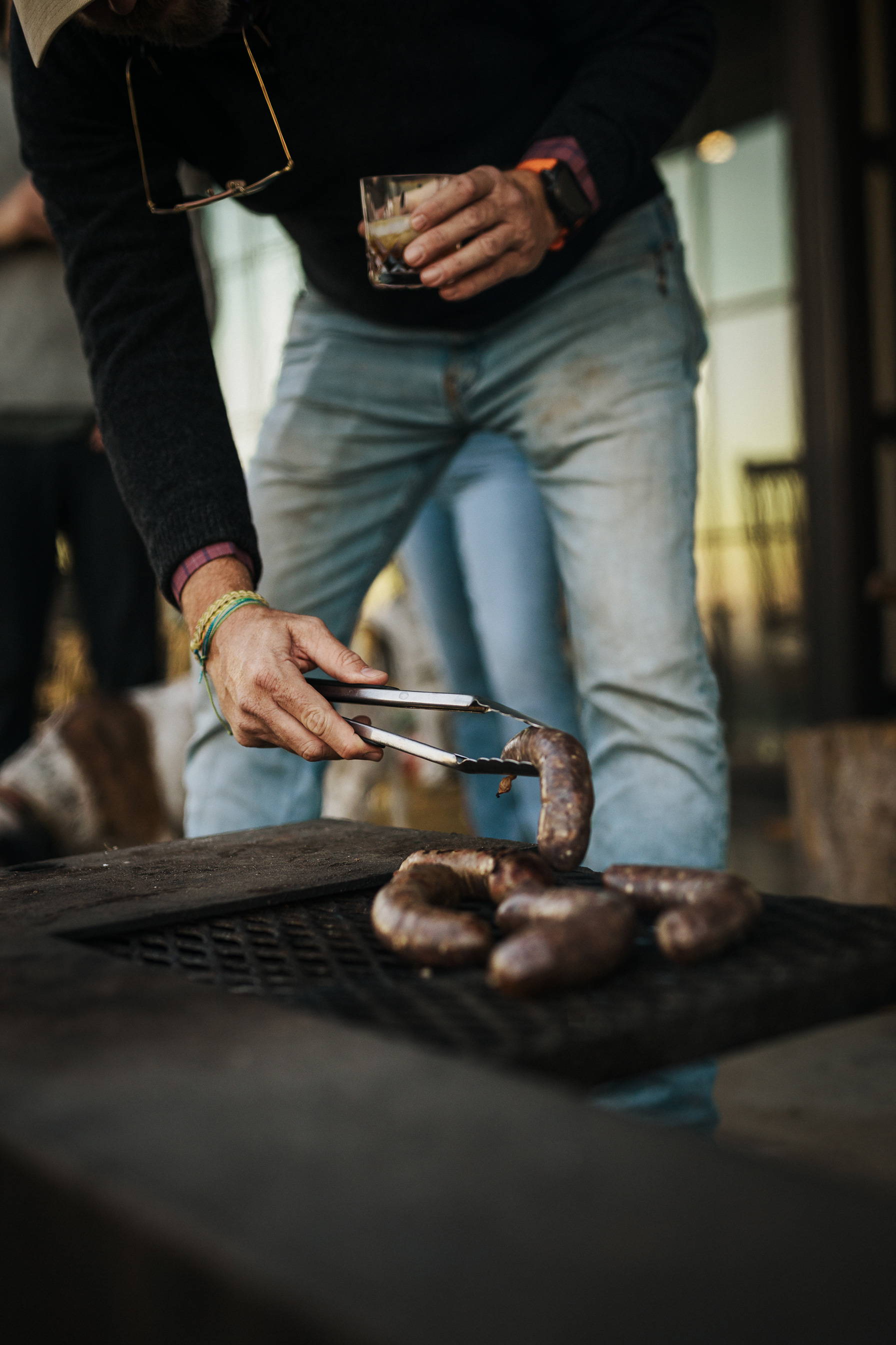 A man flipping sausage on a grill.