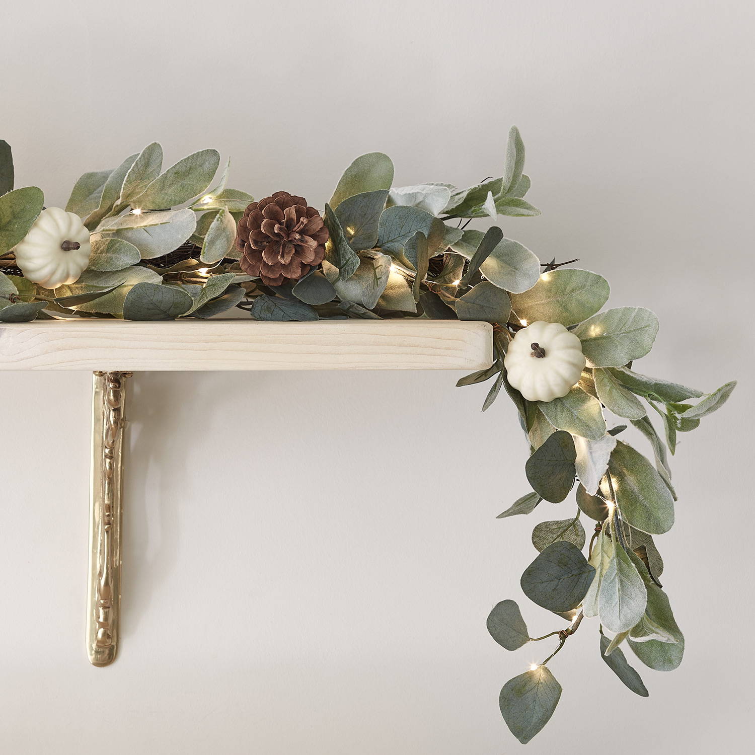 Autumnal green garland entwined in micro lights on a wall shelf