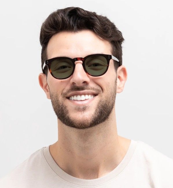 man wearing Noa round tortoise acetate sunglasses with green lenses on a white background