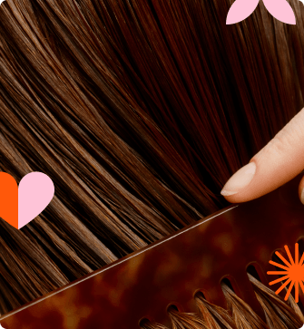 A close-up of brown hair being combed with decorative elements.