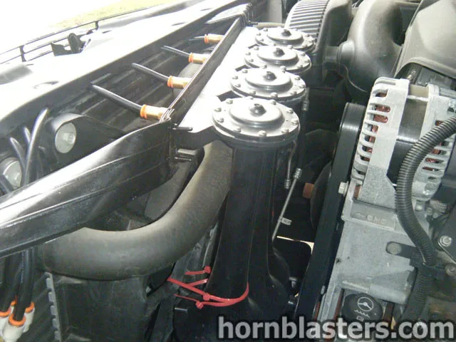 Engine bay view of train horn installation and horn hardware