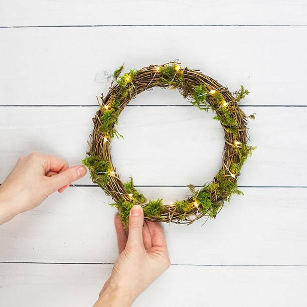 Person entwining warm white micro lights around the Easter DIY wreath.