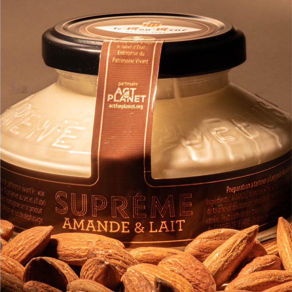 Jar of almond and milk spread surrounded by almonds.