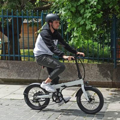 A young man riding his folding electric bike riding through the streets.