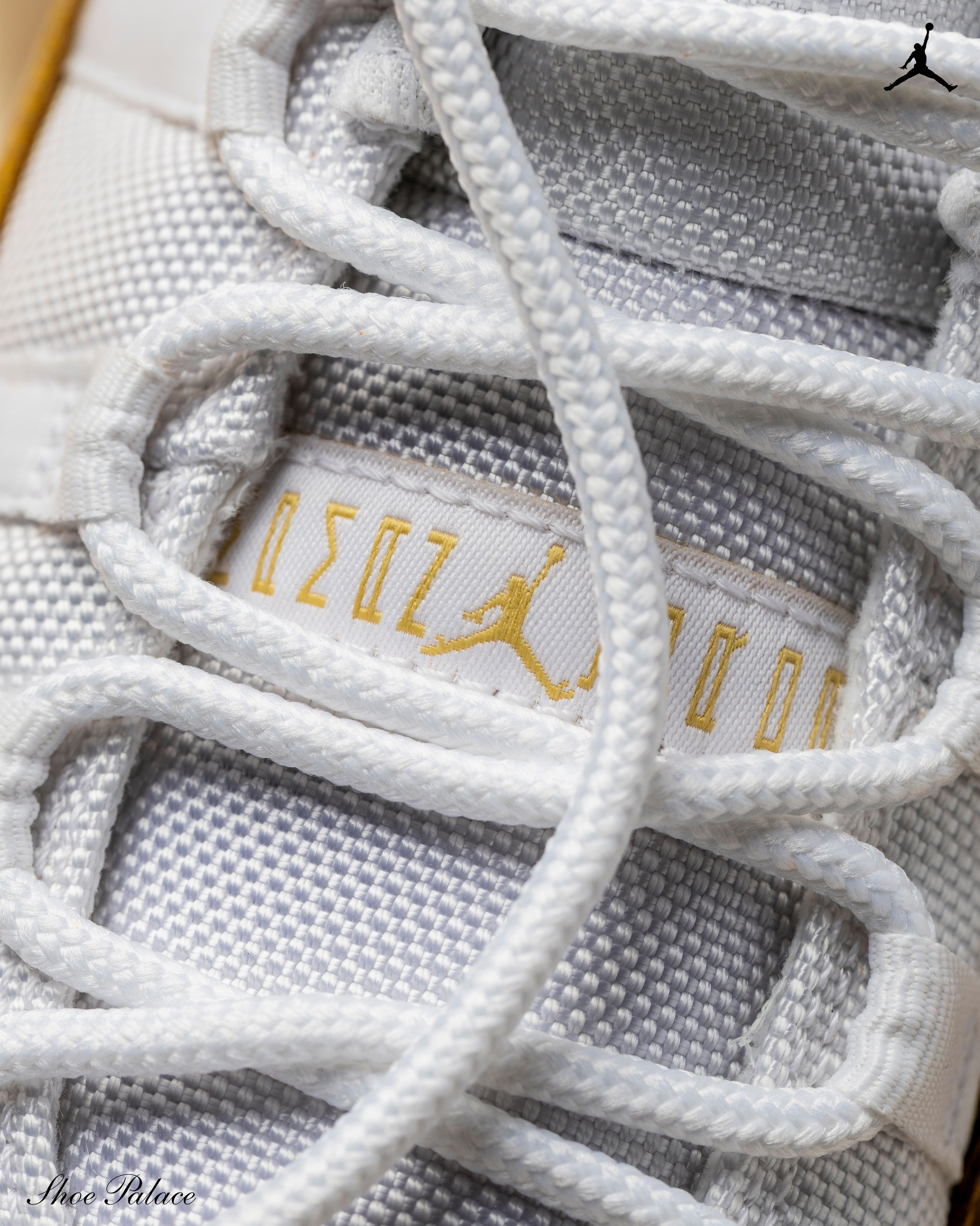 Close-up of a white sneaker with laces and branding.