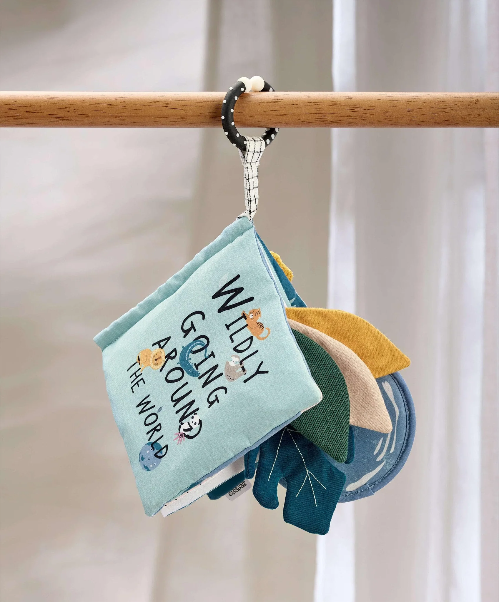 Fabric book with colorful pages hanging on a wooden rod.