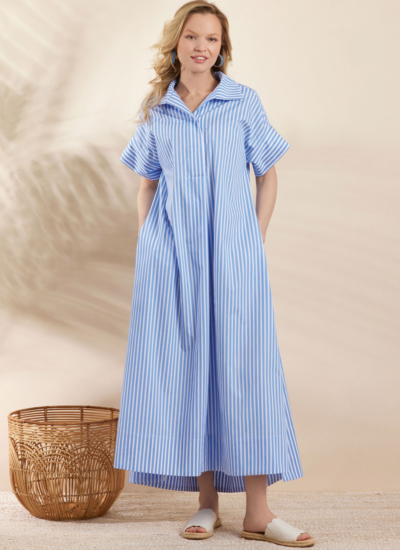 Woman in a blue striped dress standing next to a woven basket.