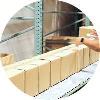 Person packing boxes on a conveyor belt in a warehouse setting.