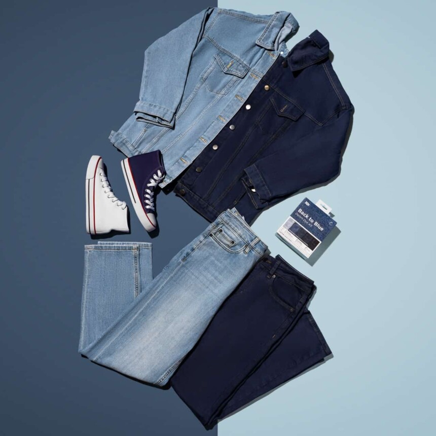 Flat lay of denim clothing and sneakers on a two-tone background.