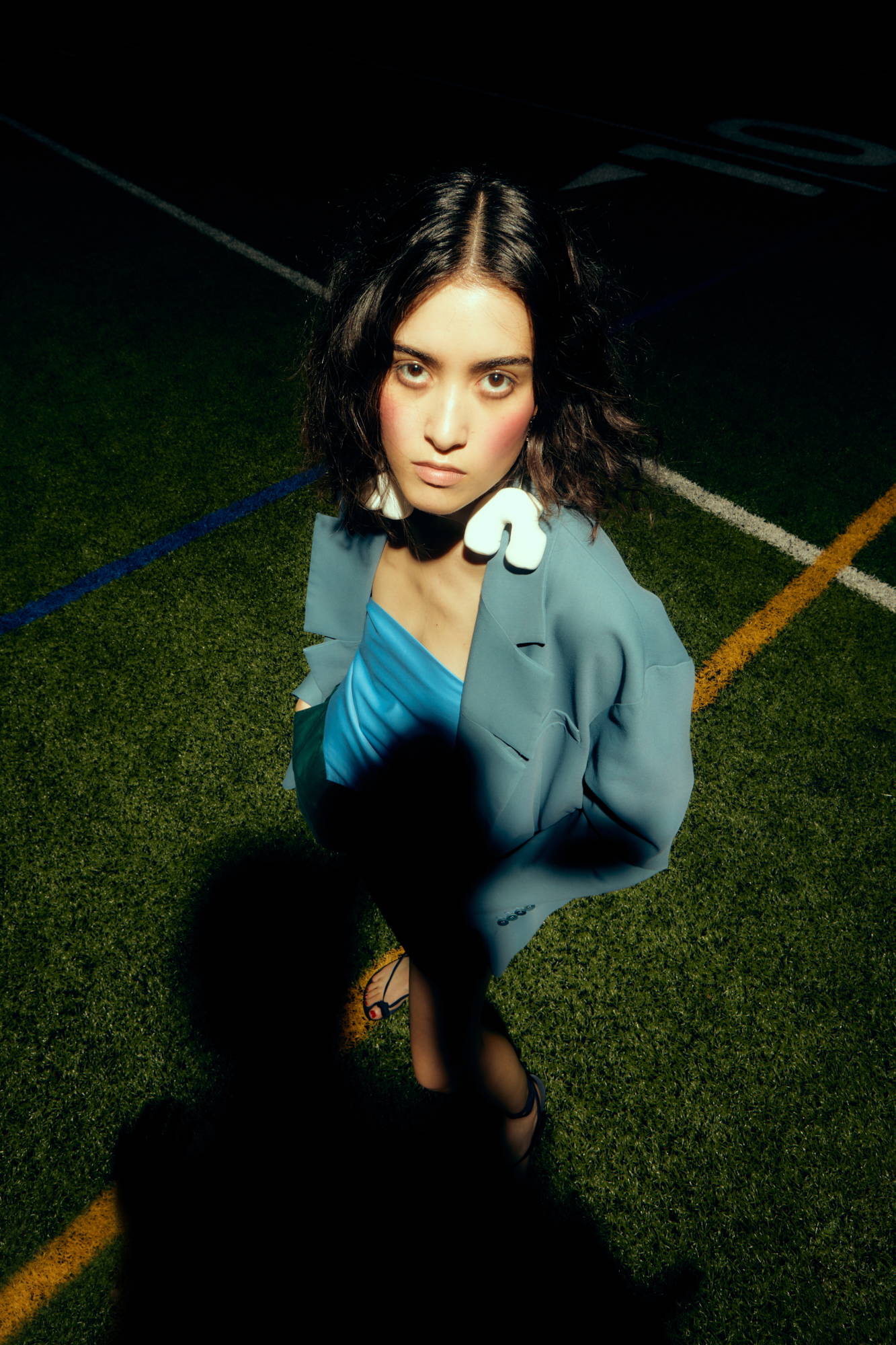A woman poses in a blue outfit on a sports field.