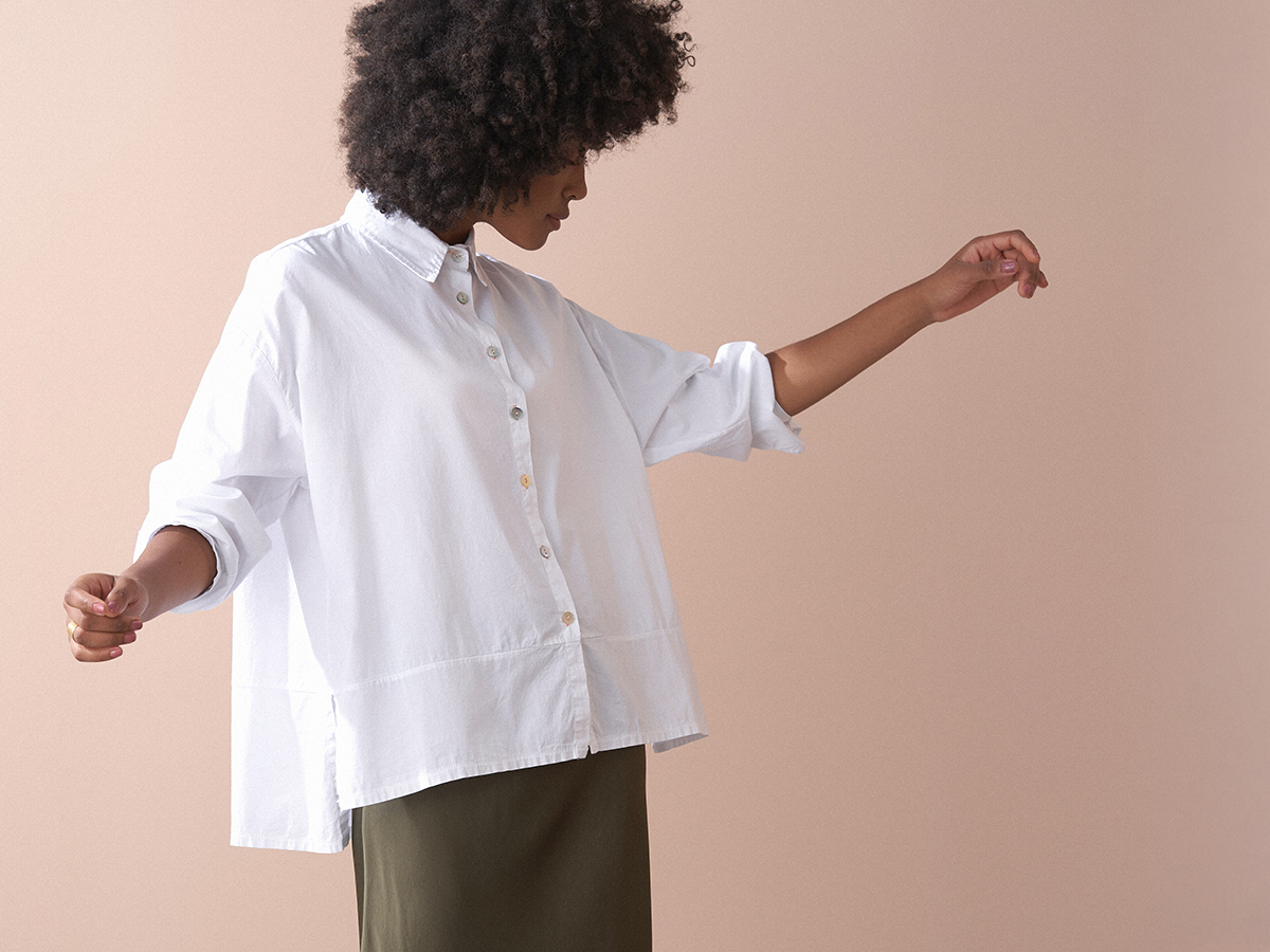Woman wearing a white, boxy cotton shirt with satin skirt