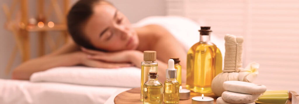 Woman relaxing at a spa with essential oils and massage products.
