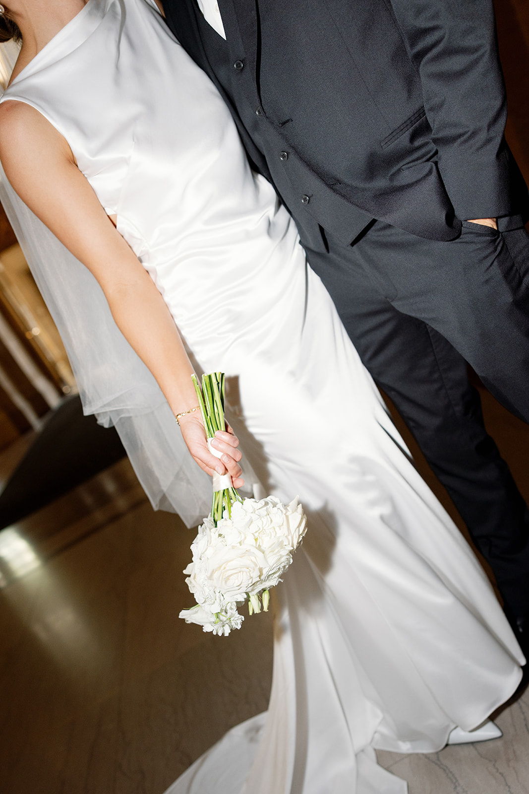 Bride in white dress holding bouquet, standing beside a groom in a suit.