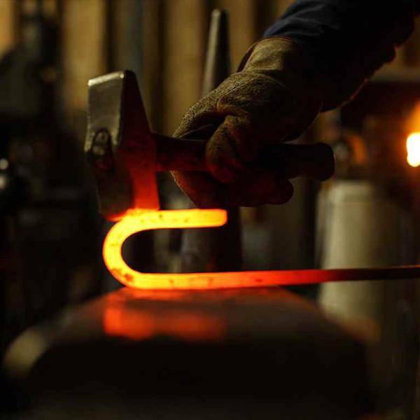 Blacksmith forging RealCraft's Classic Flat Track hanger by RealCraft. 