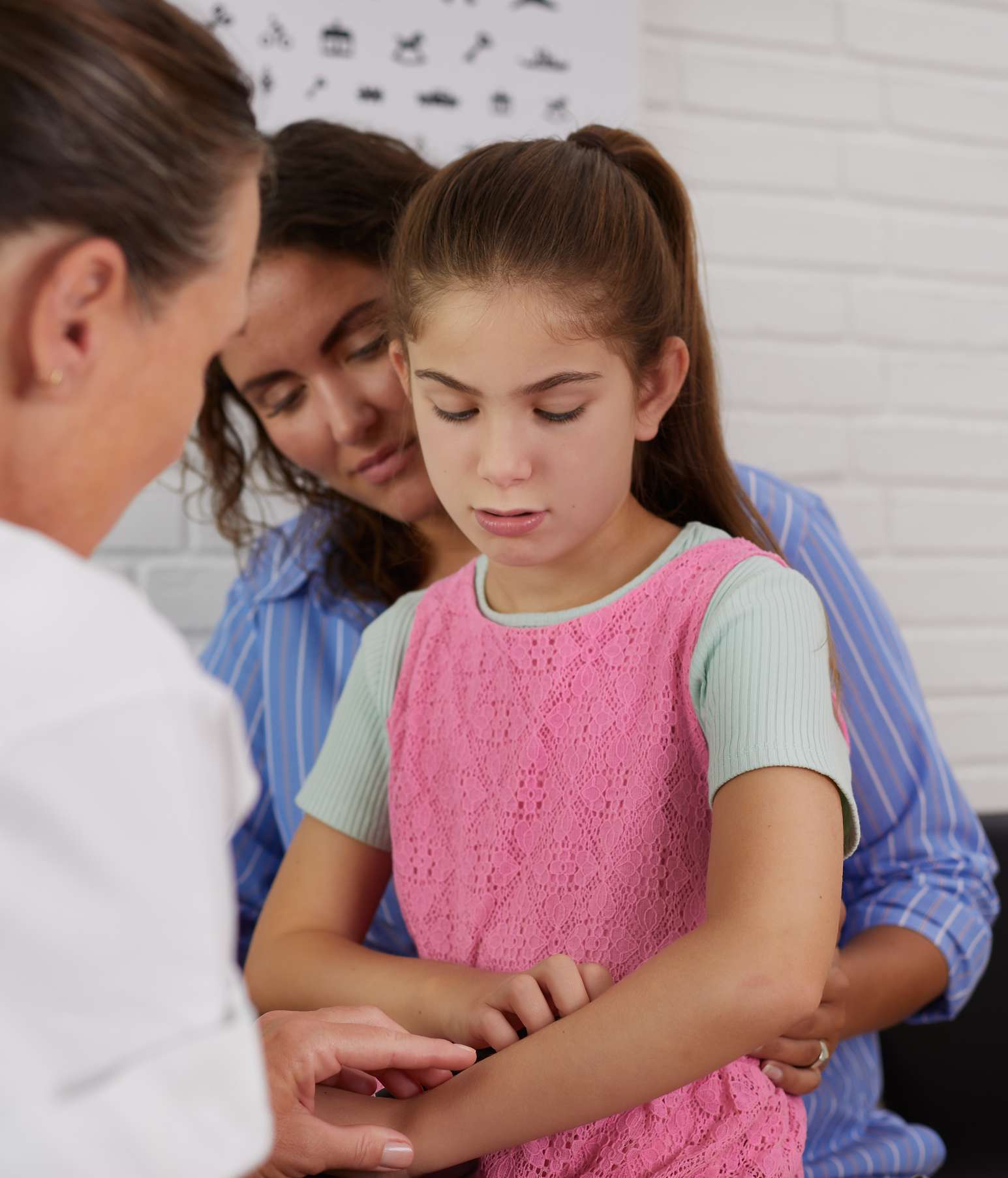 Child sitting on her mother’s knee. They’re discussing doing an allergy test. 