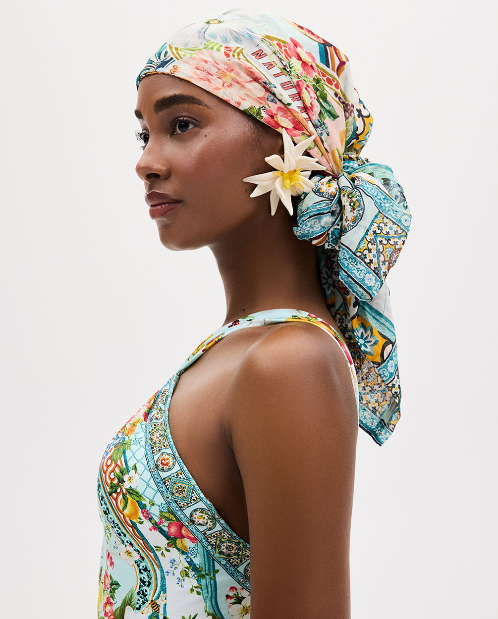 Profile of a woman in a colorful headscarf and floral dress.