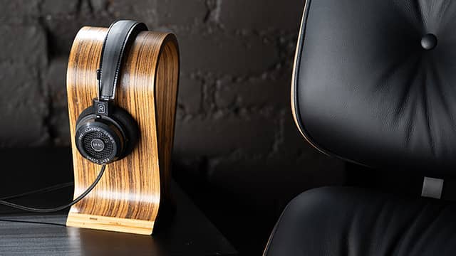 Headphones resting on a wooden stand beside a black chair.
